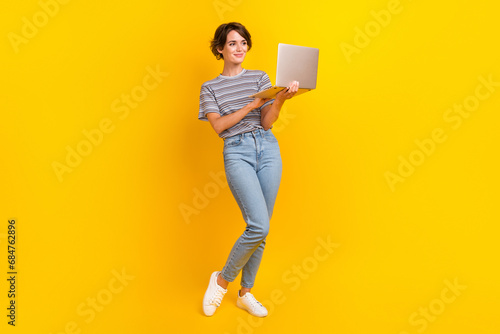 Full body portrait of gorgeous satisfied lady hold wireless netbook networking isolated on yellow color background