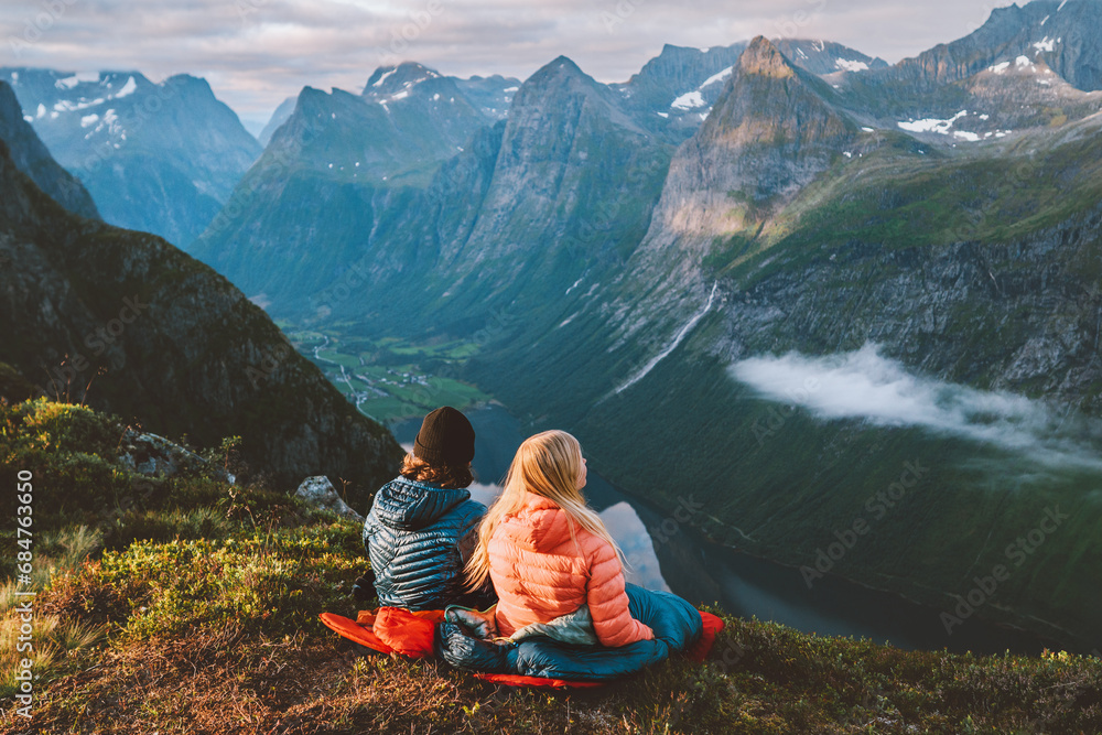 Fototapeta premium Friends couple traveling with sleeping bags enjoying mountains in Norway, man and woman hiking with camping gear, Valentines day bivouac outdoor vacations active healthy lifestyle adventure journey
