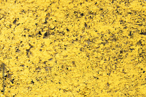 Yellow paint on black surface. Stucco wall texture. Yellow paint asphalt. Distressed noise backdrop for graphic design. Cracked asphalt texture. Grainy yellow paint background. Grunge noise backdrop.
