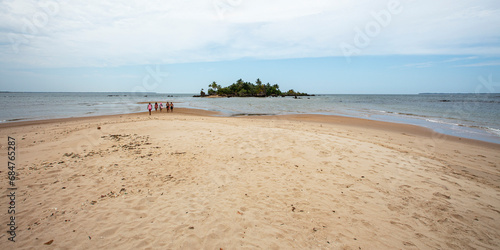 Pessoas distantes caminhando na areia da praia em direção a uma ilha no nordeste brasileiro photo