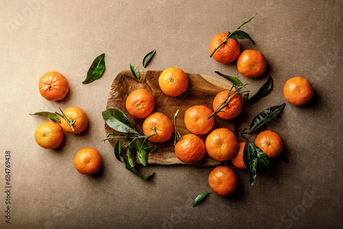 Mandarin oranges, clementines or tangerines with leaves on a dark background, top view photo