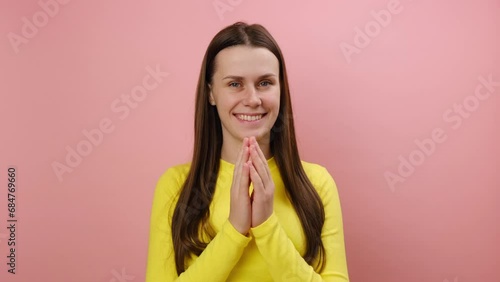 Tricky cunning smiling young caucasian woman standing looking at camera, planning something, pranking somebody, wearing yellow sweater, posing isolated over pink color background wall in studio
