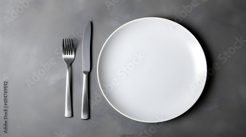 White plate with with silver cutlery on grey background