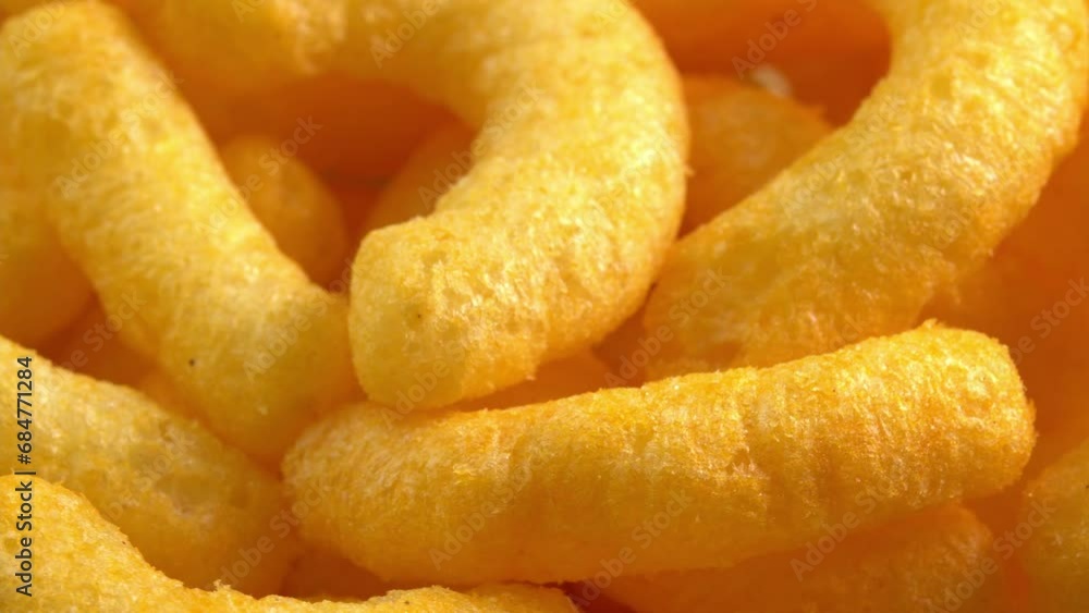 Cheesy corn sticks rotates closeup. Crispy cheese snack. Crispy fluffy corn chips for breakfast Cheesy corn sticks rotates closeup. Crispy cheese snack. Crispy fluffy corn chips for breakfast