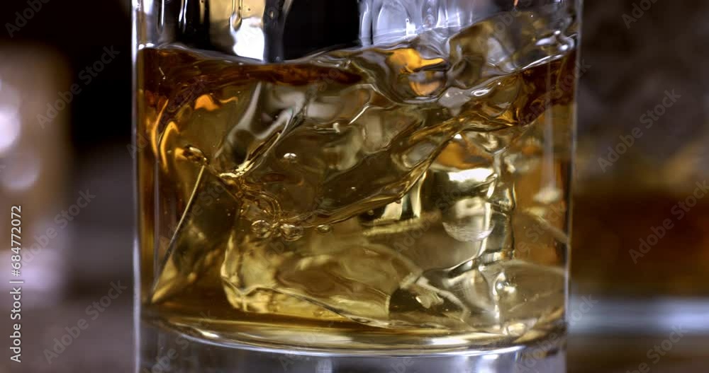 Super Slow Motion Detail Shot of Pouring old malt burbon Whiskey on Ice Cubes into pure Glass at 1000fps. Super Slow Motion Detail Shot of Pouring old malt burbon Whiskey on Ice Cubes into pure Glass at 1000fps.