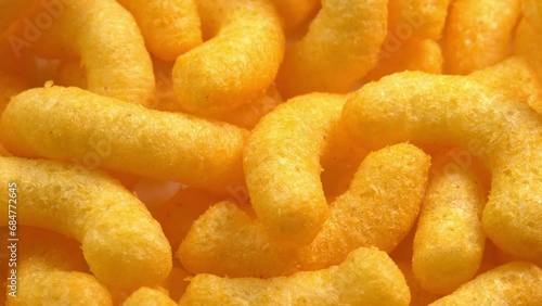 Cheesy corn sticks rotates closeup side light. Crispy cheese snack. Crispy fluffy corn chips for breakfast