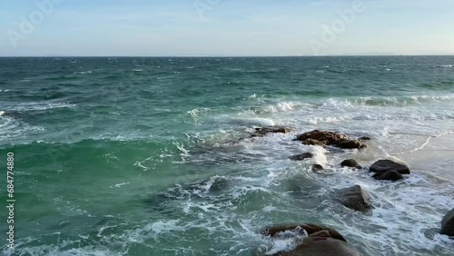 Outdoor scenery view over sea waves with clear water crushing over the rocks during beautiful sunny day. 