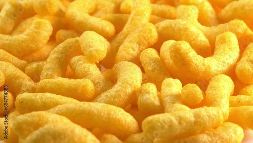 Cheesy corn chips rotates on plate side light. Crispy cheese snack. Crispy fluffy corn sticks for breakfast photo