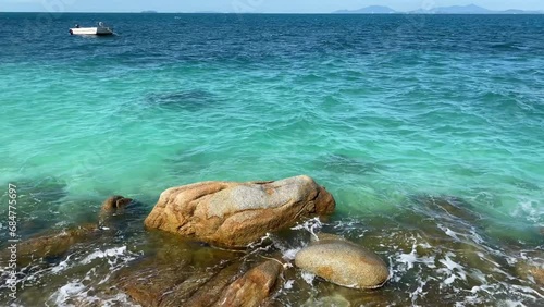 Outdoor scenery view over sea waves with clear water crushing over the rocks during beautiful sunny day. 