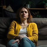A girl is sitting on the couch at home, sad and depressed