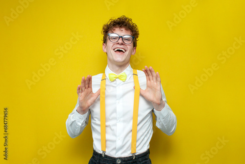 confident cheerful guy in festive outfit and glasses rejoice, nerd student in bow-tie shirt and suspenders photo