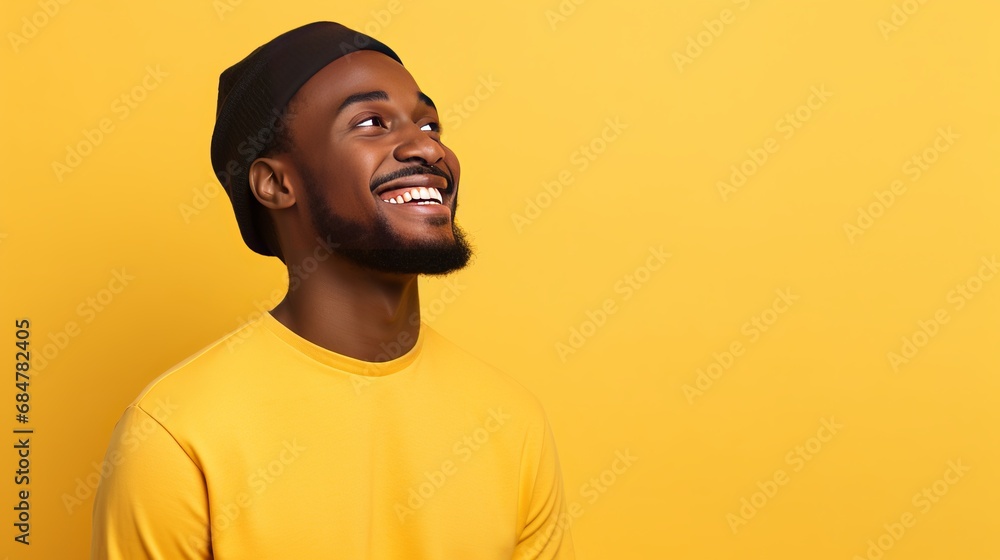 A young black man is alone on a yellow background, looking up and thinking of an idea A young black man is alone on a yellow background, looking up and thinking of an idea