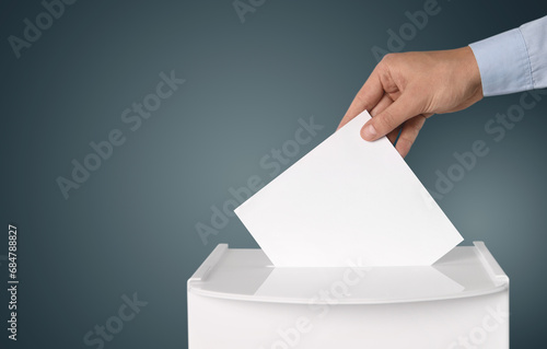 Man putting his vote into ballot box on gradient color background, closeup. Space for text