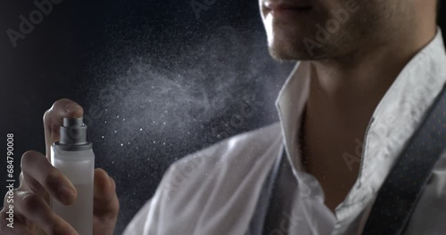 Anonymous man spraying luxury fragrance in extreme slow motion with scent particles to wet skin after dressing . concept of men's perfume and aftershave sensual men. Man perfumed after shave photo