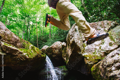A man jumps between two boulders while fly fishing in  Pisgah National Forest, North Carolina photo