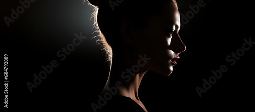  a woman's profile in the dark with her hair pulled back and her face slightly turned to the side. photo