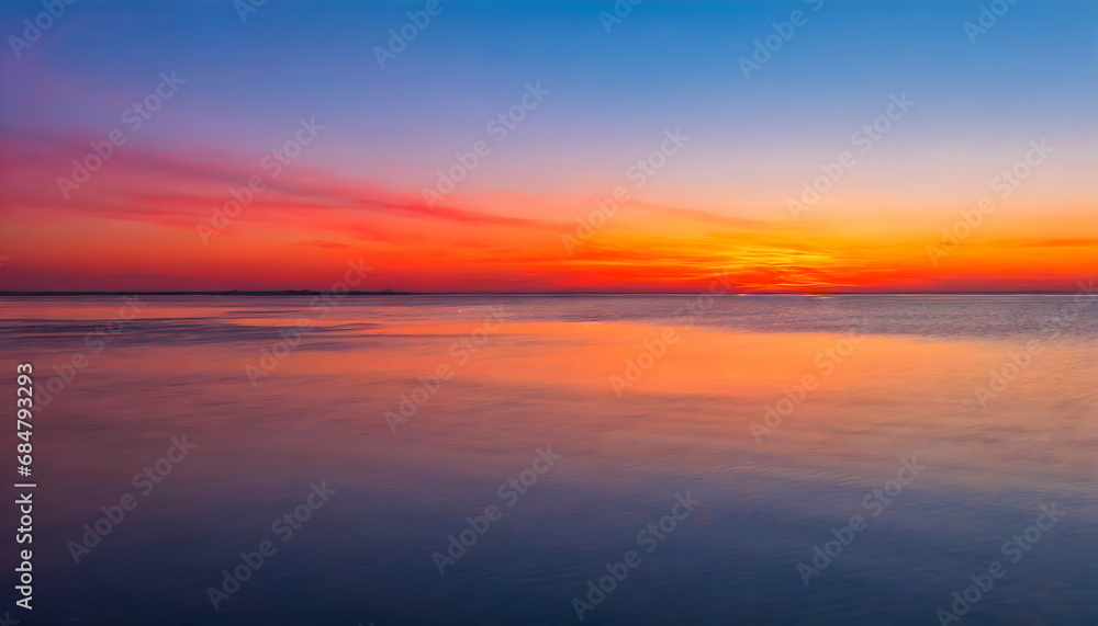 Gradient of colors in the sky as the sun sets, transitioning from warm oranges and pinks near the horizon to cool blues and purples higher in the sky. Emphasize the peaceful expanse of water.