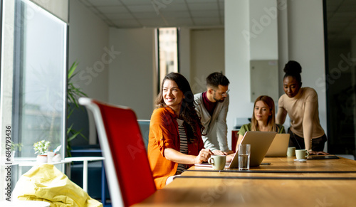 Business woman working on laptop with her young multiethnic startup team working in the modern office photo
