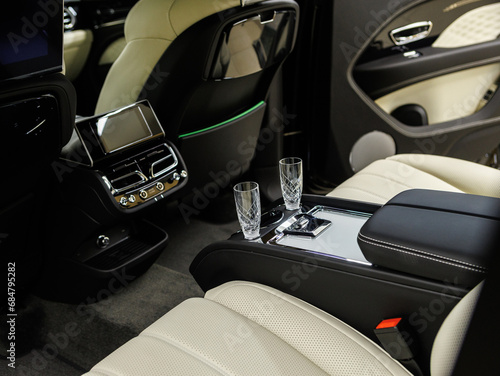 Champagne glasses in a luxury car with beige leather interior