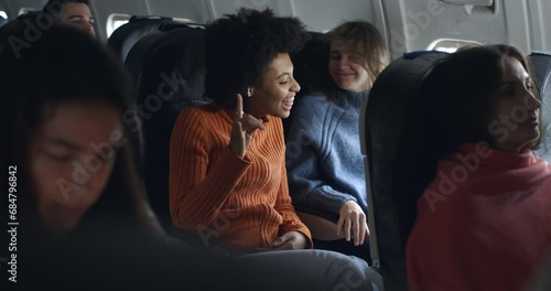 african girl and blonde friend in airplane have a humor moment with hard rock metal music and having fun together in friendship during the flight from the distant airport. photo