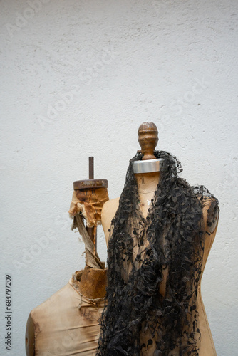 black and white of old sewing mannequins side by side with black lace shawl or scarf around neck other older and broken ripped vertical image space on top for type sewing clothing vintage backdrop  photo