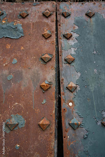 rusty metal anyique grunge doors wiht diamond shaped studs blue and rust colored weathered metal close up backdrop ir background vertical room for type heavy duty industrial metal door panels grungy