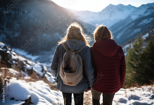Two young women hold hands during hiking on the mountain