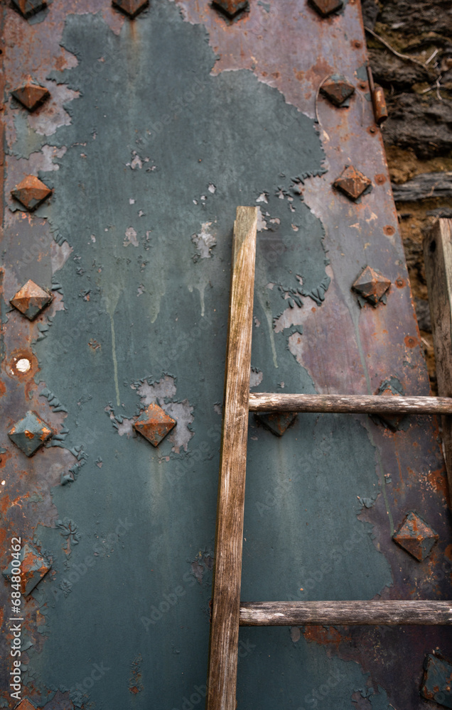 wooden ladder leaning against rust and blue rusty metal grunge grungy antique old weathered textured background or backdrop empty space for type vertical image antique blue and rust colored metal wooden ladder leaning against rust and blue rusty metal grunge grungy antique old weathered textured background or backdrop empty space for type vertical image antique blue and rust colored metal