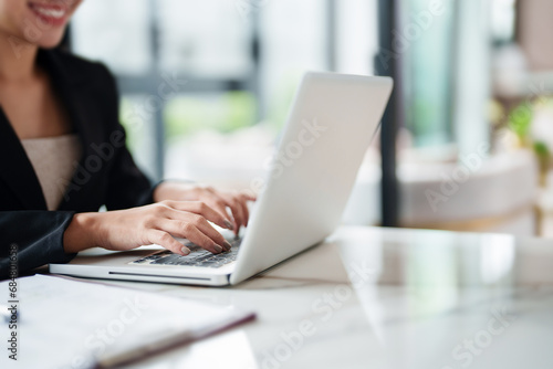 Woman using laptop working at contemporary office workplace.