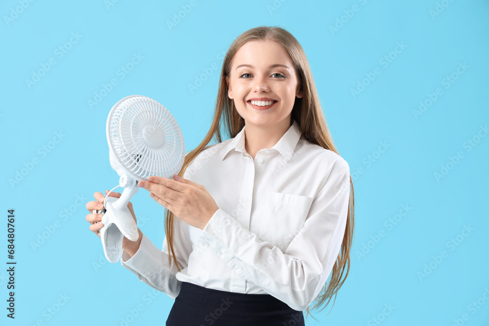 Young businesswoman with electric fan on blue background Young businesswoman with electric fan on blue background