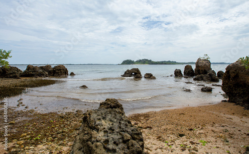 Praia de ilha repleta de pedras e grandes rochas, sem pessoas, no nordeste brasileiro. photo