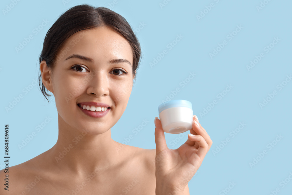 Beautiful Asian woman with jar of cream on blue background, closeup Beautiful Asian woman with jar of cream on blue background, closeup
