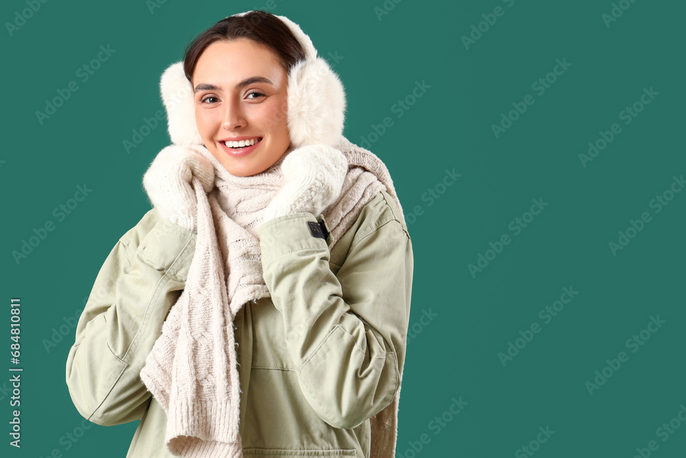Young woman in winter clothes on green background Young woman in winter clothes on green background