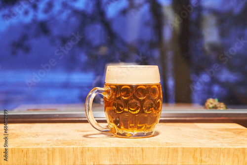 Mug of famous czech pilsner lager beer in front of window during the cold winter evening. Special kind of christmas beer is traditional alkoholic drink brewed for the christmas time in Czech Republic.