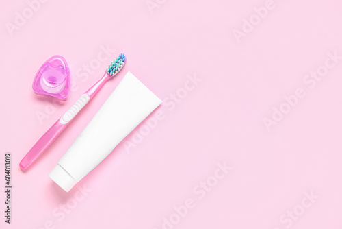 Toothbrush with toothpaste and dental floss on color background.