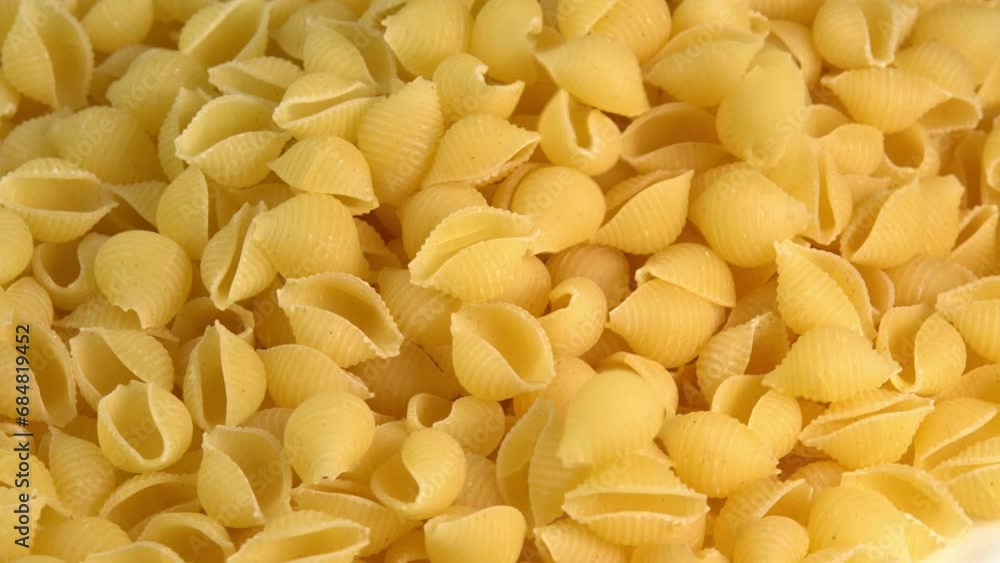 Italian pasta conchiglie rigate shell shaped falling down background closeup top view. Durum wheat flour macaroni conchigliette