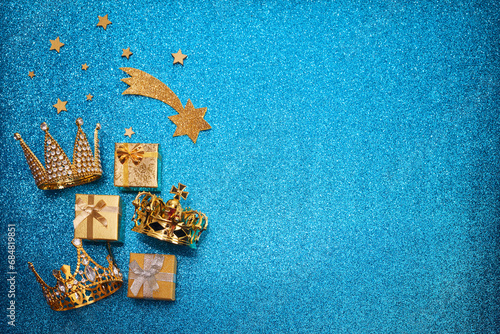 Epiphany Day or Dia de Reyes Magos concept. Three gold crowns and gifts on blue sparkling background photo