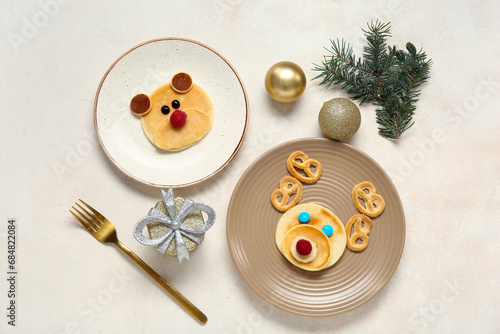Plates with pancakes in shape of reindeer and bear on white table. Christmas celebration