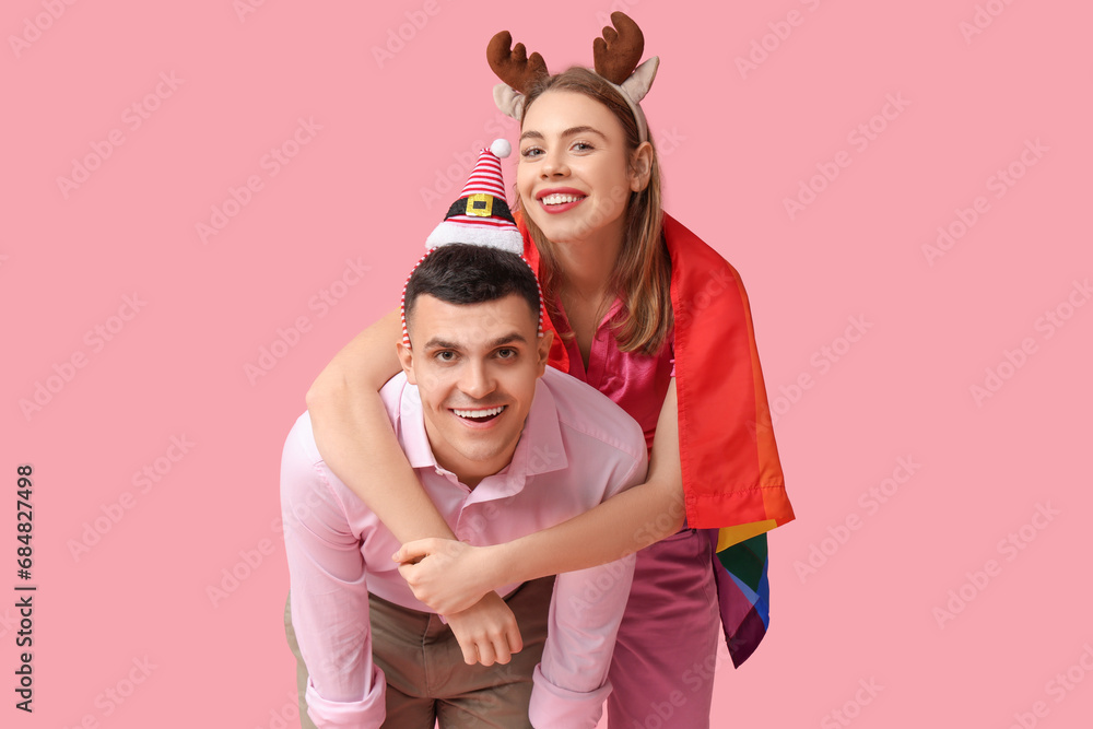 Obraz premium Young couple with LGBT flag on pink background