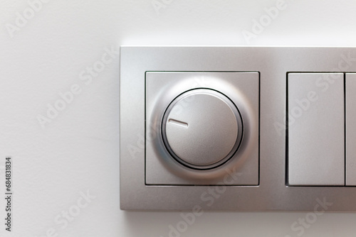 Modern smart rotary knob light dimmer light switch mounted on a wall, front view, frontal shot, object detail closeup. Dimming lights round button, circle, smart home lighting controls simple concept