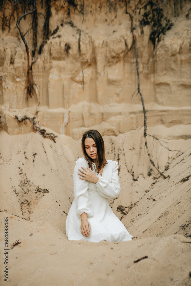 a girl in a white dress on a sand quarry a girl in a white dress on a sand quarry