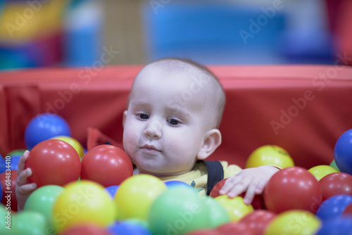 a one-year-old child, a boy, a joyful kid in toys, a lot of balls