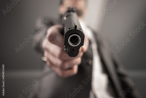 A man in a suit pointed a gun © Daniel