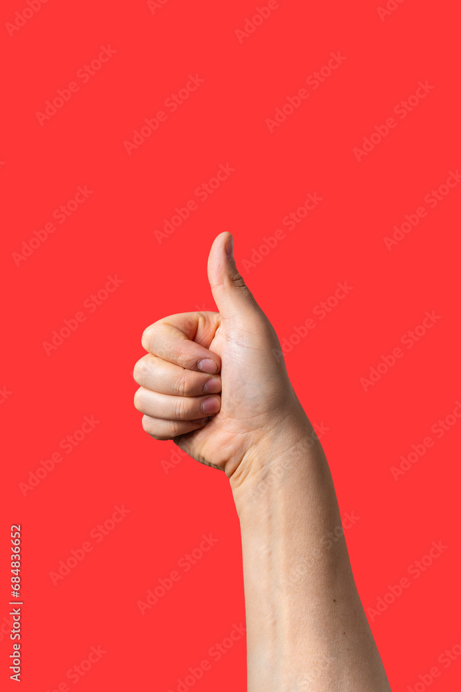 Close-up of a male arm doing thumb up sign isolated on red background
