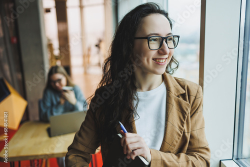 Portrait of a pretty woman in the office. Modern young manager standing in the office near the window.