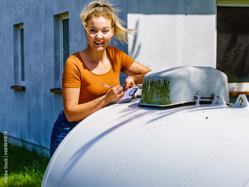 Woman checking level of propane gas in tank © Voyagerix