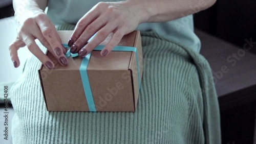 Close up slow motion footage of the woman unwrapping the gift. Concept