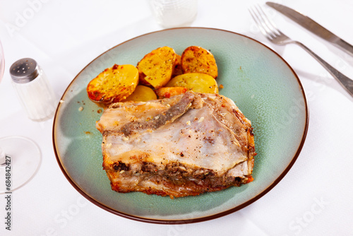 Appetizing baked pork ribs, sprinkled with fragrant seasonings on top, are served with fried sliced potatoes