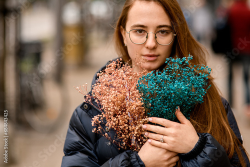Photography Young pretty brown-haired girl stands on a city street with a bouquet