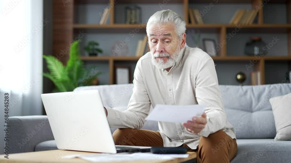 Puzzled elderly senior man having difficulty with calculating household finances using laptop sitting on sofa in room at home. Frustrated mature male confused in paperwork cannot understand problem Puzzled elderly senior man having difficulty with calculating household finances using laptop sitting on sofa in room at home. Frustrated mature male confused in paperwork cannot understand problem